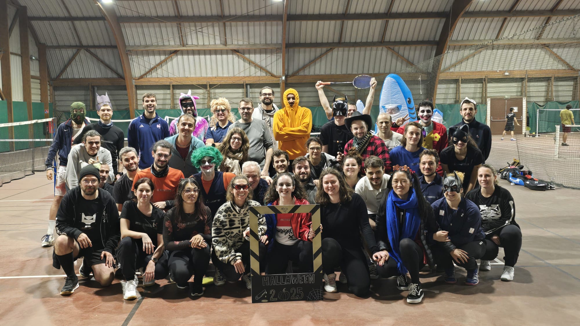 Grande photo de groupe prise pendant un tournoi déguisé de badminton