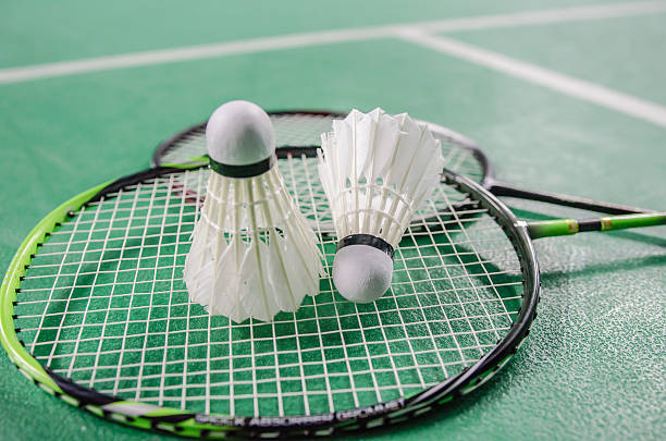 Raquette de badminton avec des volants en plume et en plastique sur un terrain